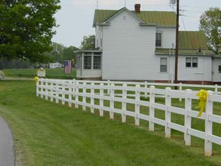 Yellow Ribbons on white pasture fence